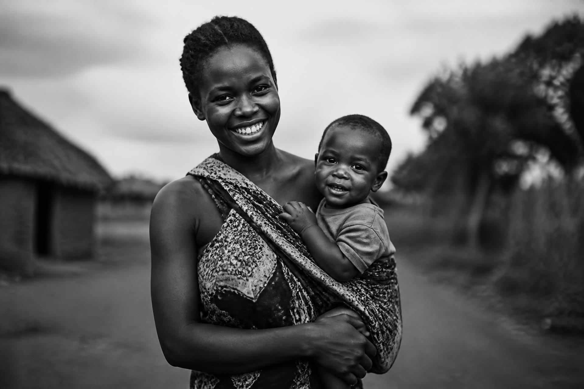 A young Kenyan mother carrying her child, smiling